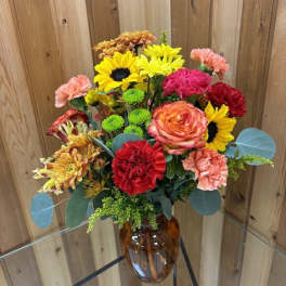 Mixed bouquet of bright flowers in an amber glass vase
