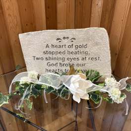Memorial stone with white floral garland and ribbon