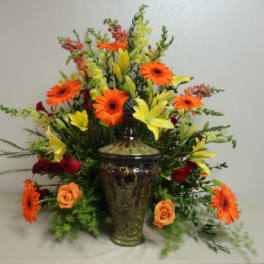Orange gerbera daisies and yellow lilies in a decorative vase