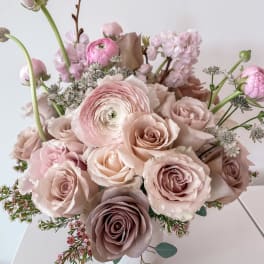 Blush roses and pink ranunculus arranged in a white vase