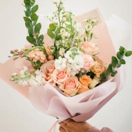 Handheld bouquet of peach and white roses with airy white blooms