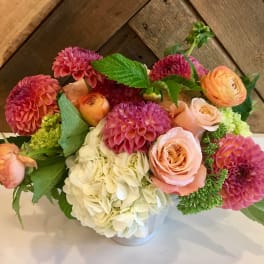 Pink and peach flowers arranged in a white vase