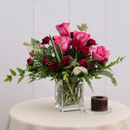 Pink and red roses arranged in a clear glass vase