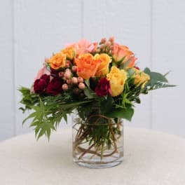 Mixed roses in a clear glass vase with greenery