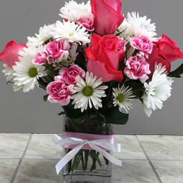 Pink roses and white daisies in a glass vase with a ribbon