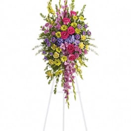 Tall standing floral spray with pink, purple, and yellow flowers on an easel