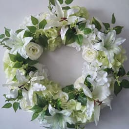 White floral wreath with lilies, roses, and hydrangeas