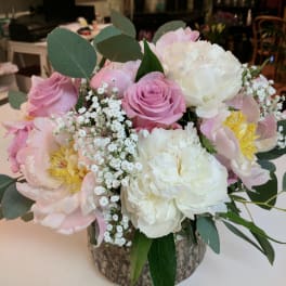 Pink and white bouquet with roses and peonies in a rustic vase