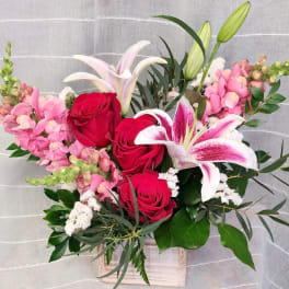 Bouquet of red roses and pink lilies in a wooden box