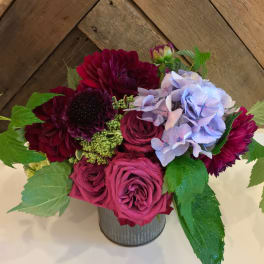 Bouquet of burgundy and pink roses with purple flowers in a metal vase