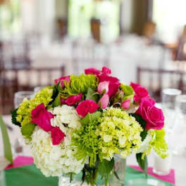 Pink and green floral centerpiece in a square glass vase