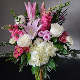 Pink lilies, white roses, and hydrangeas in a glass vase