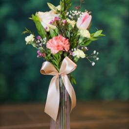 Pink and white bouquet in a tall glass vase with a satin ribbon