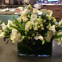 White floral arrangement in a dark rectangular vase on a countertop