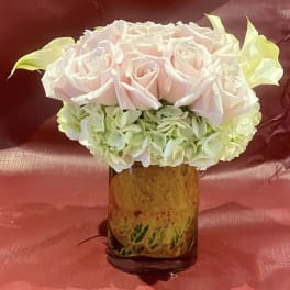 Pink roses and pale hydrangeas arranged in a glass vase.