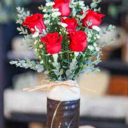 Bouquet of red roses and small white daisies in a tall vase