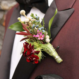 Boutonniere with red flowers and blue berries on a suit lapel