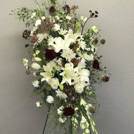 Tall white floral spray with lilies and mixed blooms on an easel