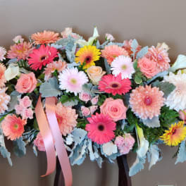Large pastel floral arrangement with pink and white blooms and ribbon