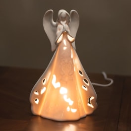 Ceramic angel figurine lamp glowing on a table