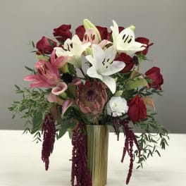 Bouquet of red roses, white lilies, and pink calla lilies in a gold vase