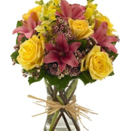 Bouquet of yellow roses and pink lilies in a glass vase