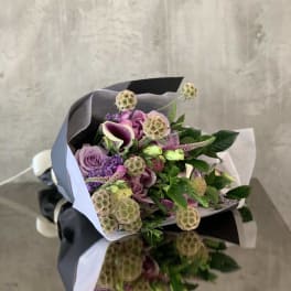 Bouquet of purple and pink flowers wrapped in black and white paper