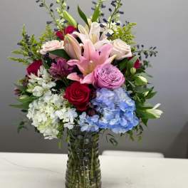 Mixed bouquet of lilies, roses, and hydrangeas in a glass vase