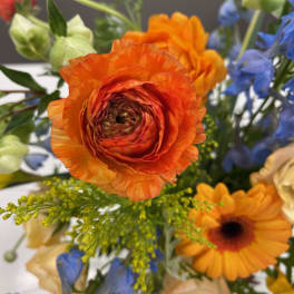 Bright mixed bouquet with orange ranunculus and blue flowers