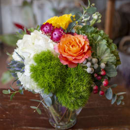 Colorful bouquet in a clear glass vase with orange, white, yellow, and pink blooms