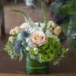 Bouquet of peach and white roses in a green glass vase