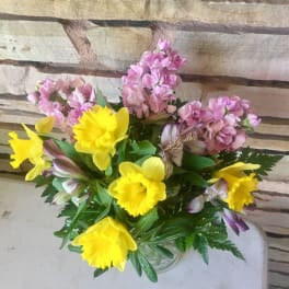 Bouquet of yellow daffodils and pink flowers in a glass vase