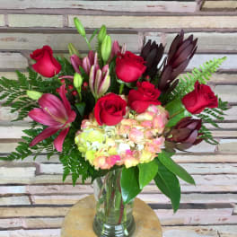Bouquet of red roses, lilies, and hydrangea in a glass vase