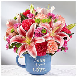 Pink lilies and roses arranged in a blue mug with text