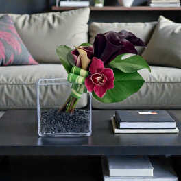 Dark purple calla lilies and orchid in a square glass vase