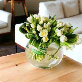 White tulips arranged in a round glass vase