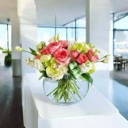 Pink and white flower arrangement in a round glass vase