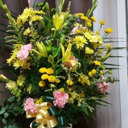 Large yellow and pink floral standing arrangement with ribbon
