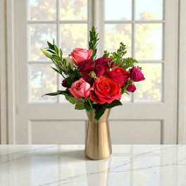 Pink and red roses arranged in a gold vase