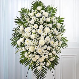 White funeral spray with palm fronds on a stand