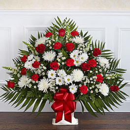 Standing floral spray with red roses and white daisies on a white easel
