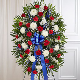 Standing funeral spray with red and white flowers and a blue ribbon