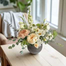 Mixed flower arrangement in a round gray vase on a table
