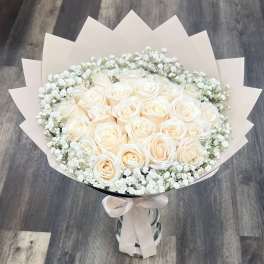 Bouquet of cream roses with white baby's breath in pale wrapping