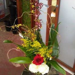 Tall floral arrangement with red and white roses and yellow blooms in a vase