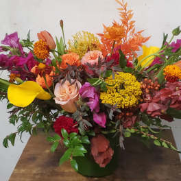 Mixed bouquet with roses, calla lilies, and bright orange and purple flowers in a vase