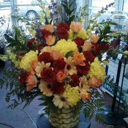 Large mixed flower arrangement in a woven basket on a stand