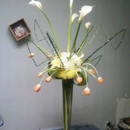 Tall floral arrangement with white calla lilies and peach tulips in a vase