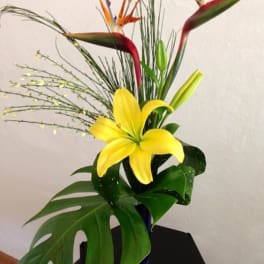 Tropical arrangement with yellow lily and bird-of-paradise flowers