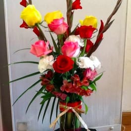 Tall bouquet of red, pink, and yellow roses in a glass vase